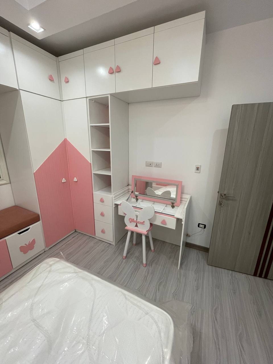 Luxury kids bedroom furniture featuring white built-in wardrobes, smart storage units, and a cozy window seating nook — elegant girls’ room design by Nido Nino.